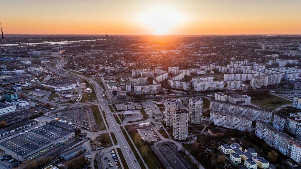 夕日が沈む都市の空撮ビュー。高層住宅と広い道路網が広がる都会の景観。