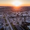 夕日が沈む都市の空撮ビュー。高層住宅と広い道路網が広がる都会の景観。