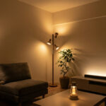 暖色の間接照明で落ち着いた雰囲気に整えたモダンなリビング。フロアランプ、テーブルランプ、テレビボード照明、観葉植物がある空間