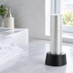 白い洗面台に置かれた白シャツと銀色の超音波衣類ケア機器。シミ抜きや毎日の衣類ケアを想起させる清潔感のある室内写真