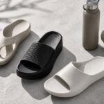 コンクリート床に並べられた白と黒の軽量サンダル、タオル、ボトル。ジムやプール、室内履きにも使いやすいリカバリーサンダルのイメージ